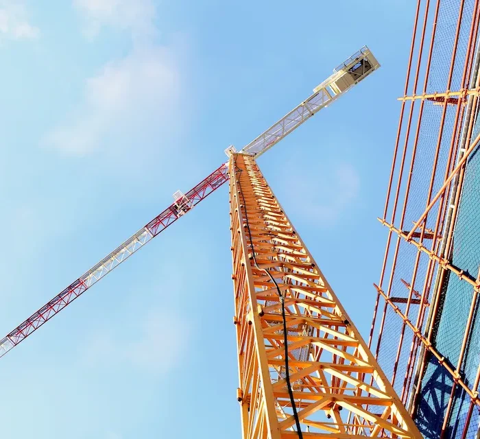 Tower crane positioned beside scaffolding systems at a large construction project in Stockton