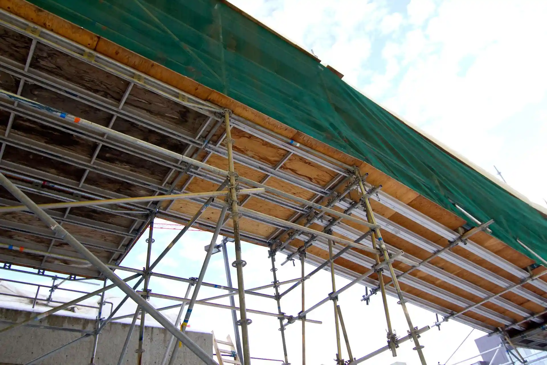 Elevated scaffolding platform with support beams and safety netting at a Stockton job site
