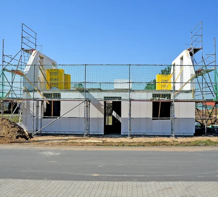 Scaffolding surrounding a modern home construction project with protective safety barriers