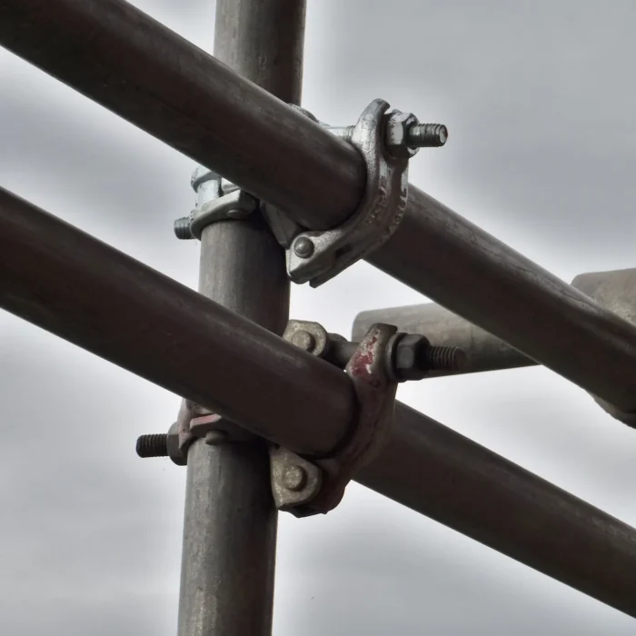 Close-up of scaffolding pipe connectors and steel clamps used on a Stockton construction site